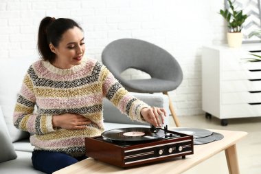 Evde kayıt oyuncusu aracılığıyla müzik dinleyen hamile kadın
