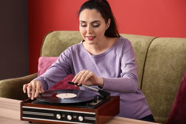 Evde kayıt oyuncusu aracılığıyla müzik dinleyen hamile kadın
