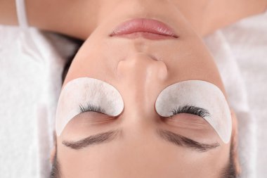 Güzellik salonunda kirpik uzatma prosedürüne tabi tutulan genç bir kadın.