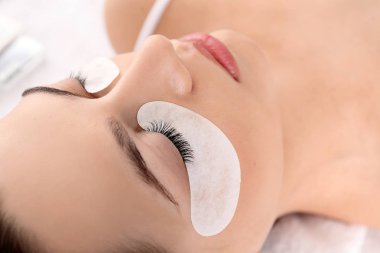 Güzellik salonunda kirpik uzatma prosedürüne tabi tutulan genç bir kadın.