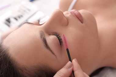 Young woman undergoing eyelash extension procedure in beauty salon clipart