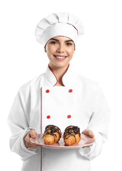 Ung kvinnlig konditor med läckra croissanter på vit bakgrund — Stockfoto