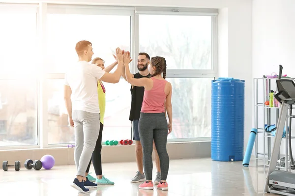 Jóvenes deportistas poniendo manos juntas en el gimnasio — Foto de Stock