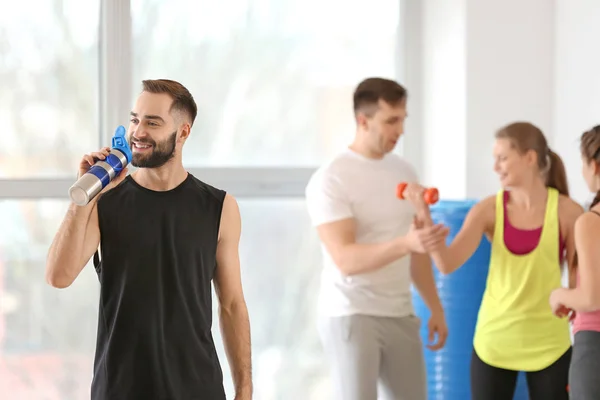 Sporty young man drinking water in gym — Stock Photo, Image