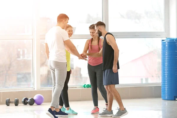 Sporty young people putting hands together in gym — Stock Photo, Image
