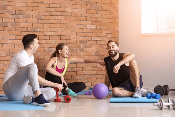 Sporty young people resting after training in gym — Stock Photo, Image