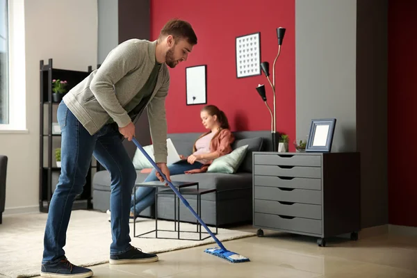 Soțul de casă curăță podeaua în timp ce soția lui lucrează acasă — Fotografie, imagine de stoc