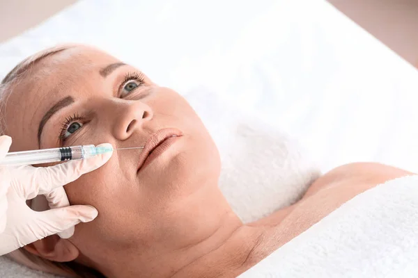 Mature woman receiving filler injection in beauty salon — Stock Photo, Image