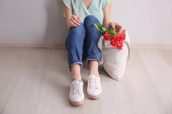 Eco bag with flowers near woman sitting on floor — Stock Photo, Image