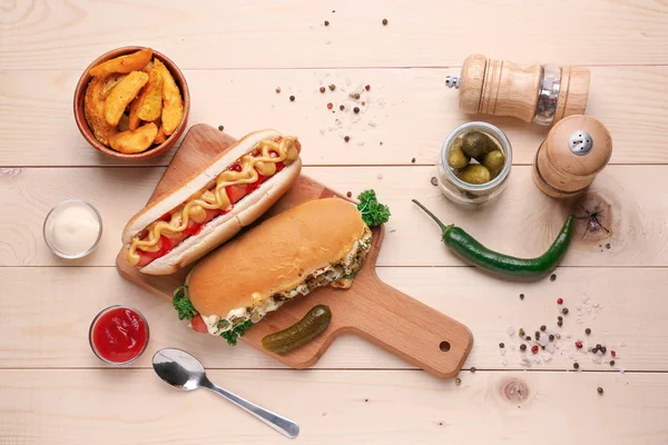 Tasty hot dogs with potato and sauces on wooden table — Stock Photo, Image