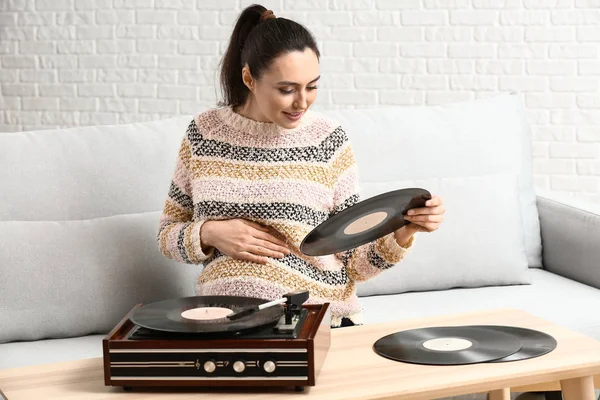 Evde kayıt oyuncusu aracılığıyla müzik dinleyen hamile kadın