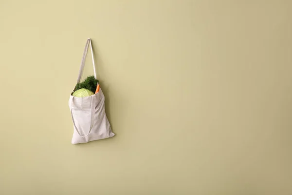 Eco bag with fresh vegetables hanging on wall