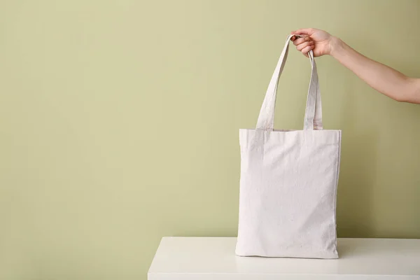 Female hand with eco bag on table against color background — Stock Photo, Image