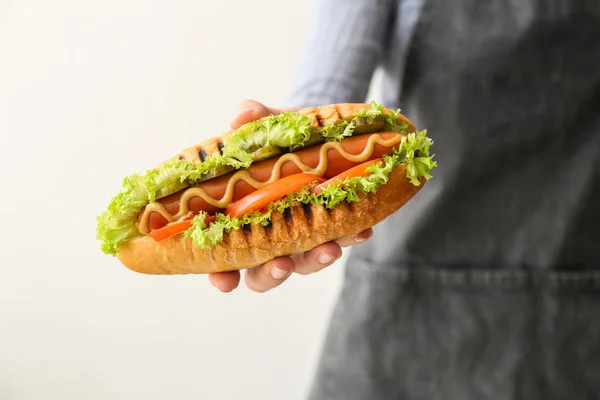 Mujer sosteniendo sabroso hot dog sobre fondo blanco — Foto de Stock