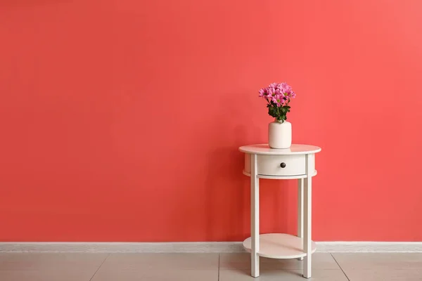 Mesa blanca con flores frescas cerca de la pared de color en la habitación —  Fotos de Stock