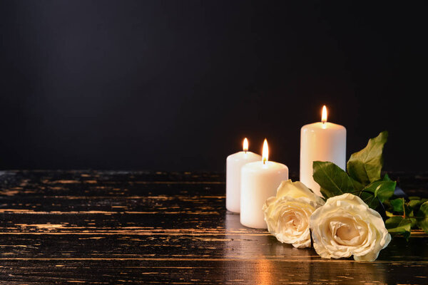 Bougies et fleurs allumées sur la table sur fond noir — Photo