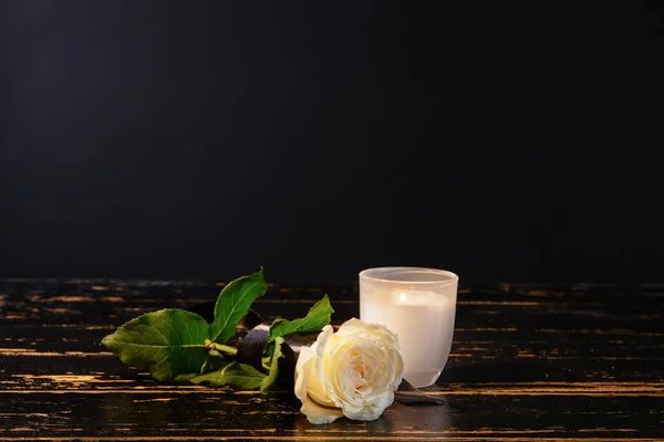 Queimando vela e flor na mesa contra fundo preto — Fotografia de Stock