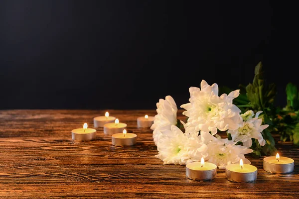 Queimando velas e flores na mesa contra fundo preto — Fotografia de Stock