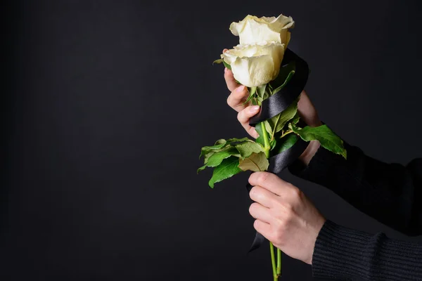 Donna in lutto con fiori e nastro nero su sfondo scuro — Foto Stock