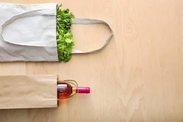 Different eco bags with products on wooden background