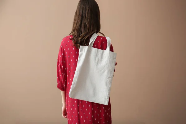 Mujer joven con bolsa ecológica en el fondo de color, vista trasera —  Fotos de Stock