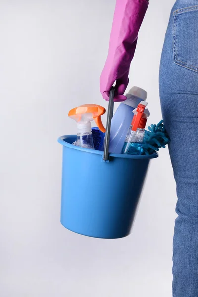 Frau mit Putzutensilien auf hellem Hintergrund — Stockfoto