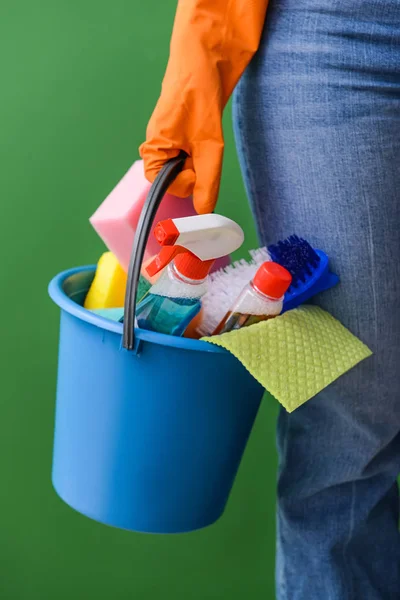 Mulher com conjunto de suprimentos de limpeza no fundo de cor — Fotografia de Stock