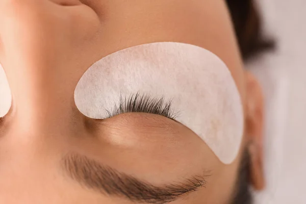 Young woman undergoing eyelash extension procedure in beauty salon, closeup — Stock Photo, Image