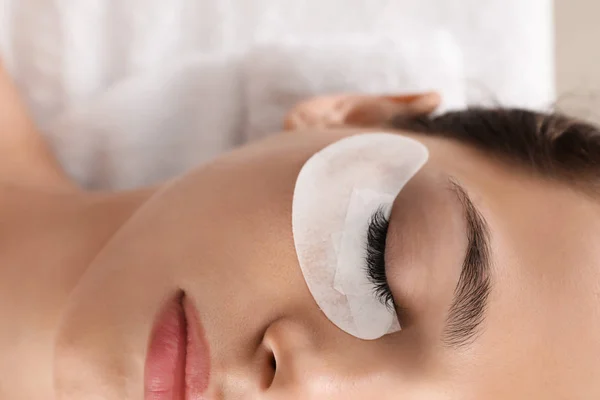 Young woman undergoing eyelash extension procedure in beauty salon, closeup — Stock Photo, Image