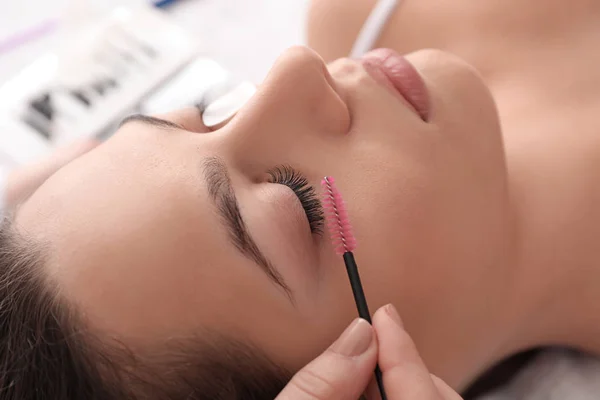 Young woman undergoing eyelash extension procedure in beauty salon — Stock Photo, Image