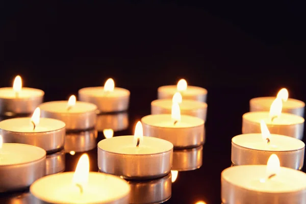 Many burning candles as symbol of mourning on dark background — Stock Photo, Image