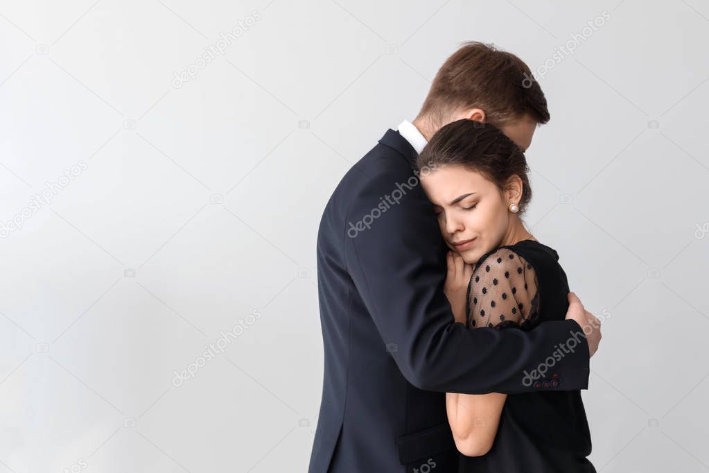 Couple pining after their relative on light background