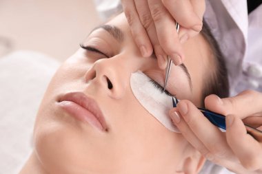 Güzellik salonunda kirpik uzatma prosedürüne tabi tutulan genç bir kadın.