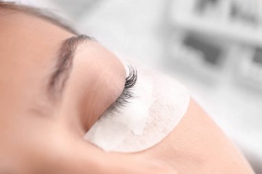 Güzellik salonunda kirpik uzatma prosedürüne tabi tutulan genç bir kadın.