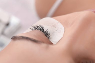 Güzellik salonunda kirpik uzatma prosedürüne tabi tutulan genç bir kadın.