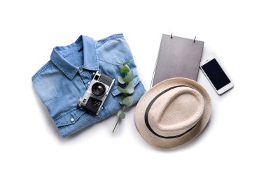 Fotoğraf makinesi, cep telefonu ve beyaz zemin üzerine şapka ile gömlek