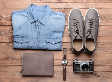 Spor ayakkabı, fotoğraf makinesi, izle ve ahşap arka plan üstünde defter ile gömlek