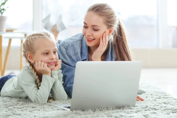 Jovem mãe com filhinha assistindo desenhos animados em casa — Fotografia de Stock