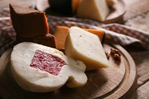 Wooden board with assortment of tasty cheese on table — Stock Photo, Image