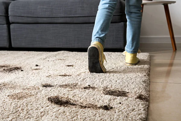 Little girl in muddy shoes messing up carpet at home — Stock Photo, Image