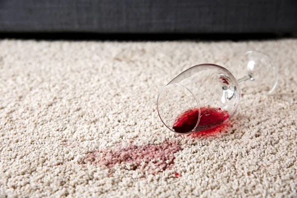 Glass of wine spilled on carpet — Stock Photo, Image