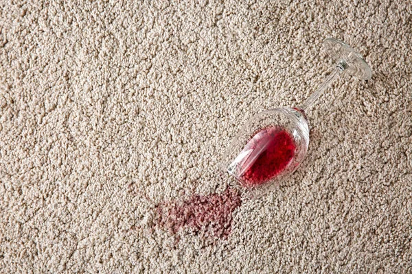 Glass of wine spilled on carpet — Stock Photo, Image