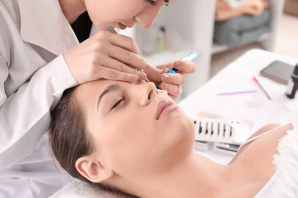 Young woman undergoing eyelash extension procedure in beauty salon — Stock Photo, Image