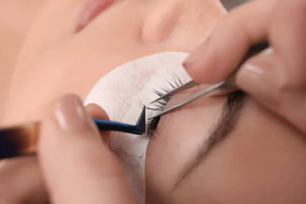 Jonge vrouw ondergaat wimper uitbreiding procedure in schoonheidssalon, close-up — Stockfoto