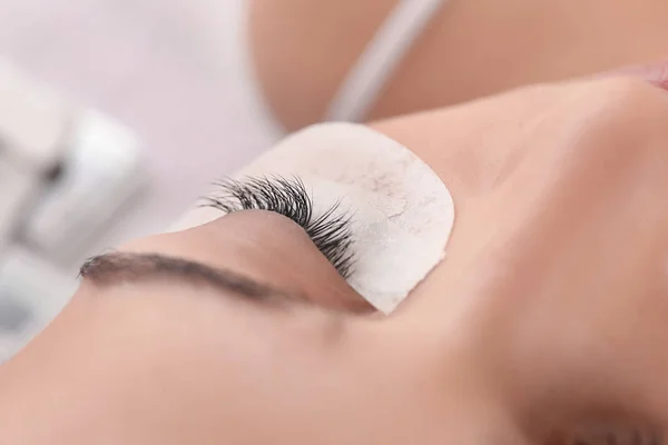 Young woman undergoing eyelash extension procedure in beauty salon, closeup — Stock Photo, Image