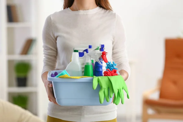 Jonge vrouw met schoonmaakmiddelen thuis — Stockfoto