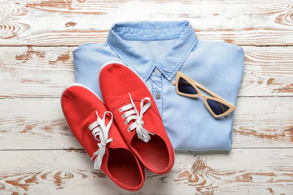 Shirt met sneakers en zonnebrillen op witte houten achtergrond — Stockfoto