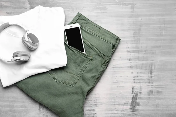 Kläder med hörlurar och mobiltelefon på grå bakgrund — Stockfoto