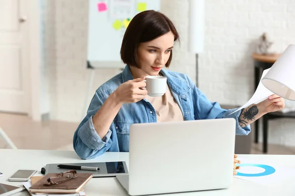 Designer feminina bebendo café enquanto trabalhava no escritório — Fotografia de Stock