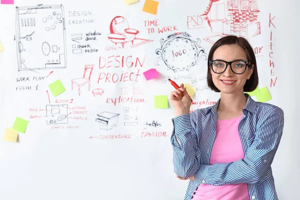 Female designer near big paper sheet with project plan in office — Stock Photo, Image